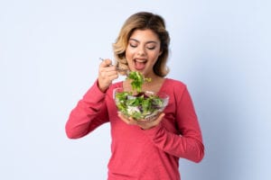 Une femme mange une salade