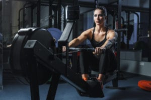 Une femme qui suit son programme d'entraînement au rameur pour maigrir dans une salle de sport