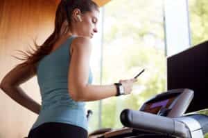 Une femme qui fait du fitness en regardant son téléphone